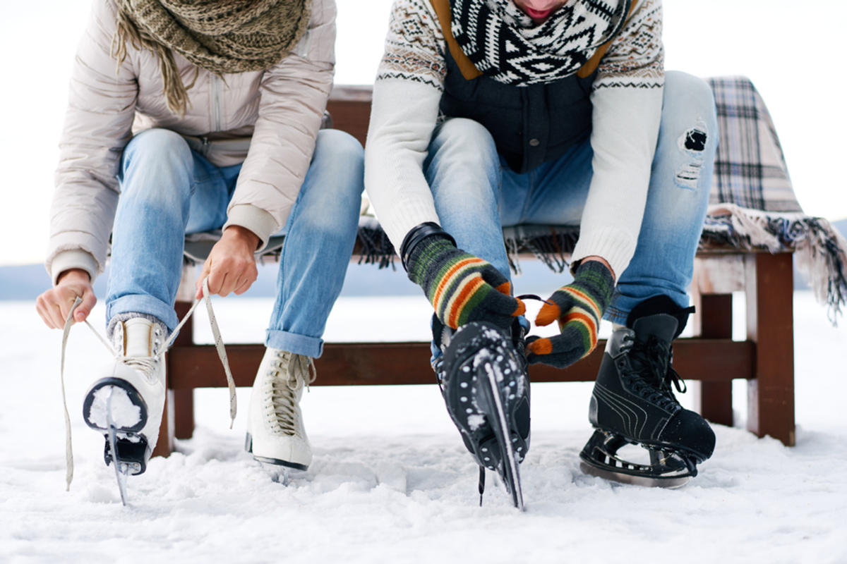 couple-putting-on-ice-skate-outdoors