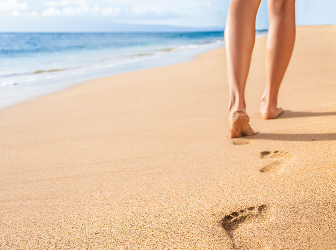 Person walking in sand leaving footprints behind