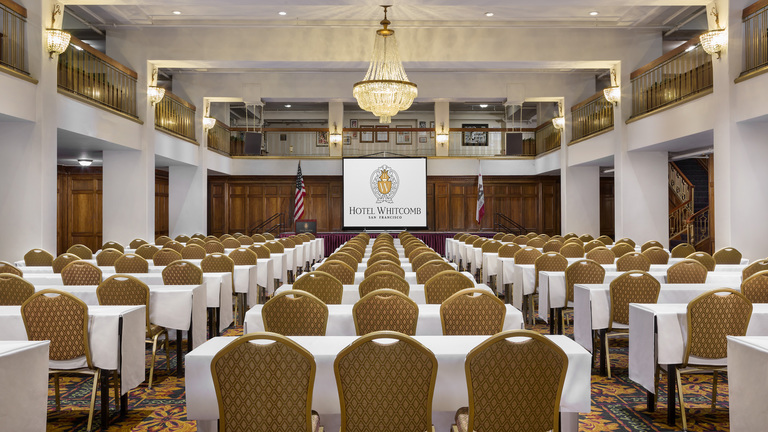 Hotel Whitcomb Ballroom Classroom with projector screen having Hotel Logo and chandelier on the roof