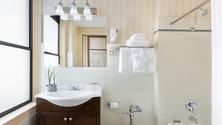 Whitcomb bathroom. To the left, sink with mirror placed on the top and, taps and showers to the right