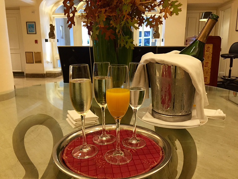 Lobby, four wine glasses placed on a tray, and next to it is a Bottle of wine in Ice Buckett